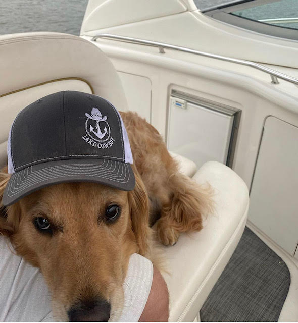 Photo of a golden retriever wearing a Lake Cowboy hat on a boat