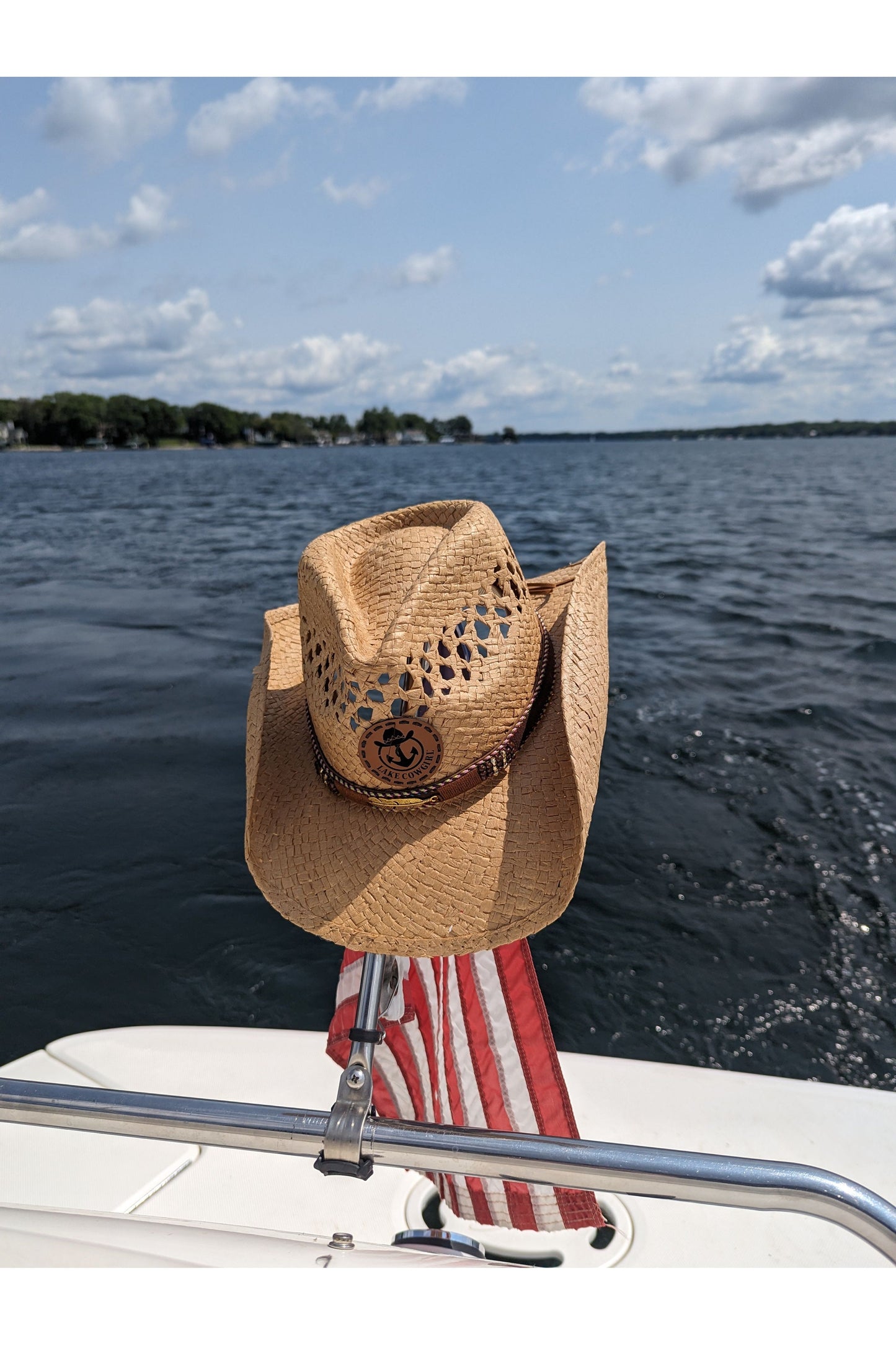 Photo of a Lake Cowgirl Signature Cowboy Hat with Feather Band (Tea Colored) – Hat is shown hanging from a boat flag on the back of a bot on Lake Minnetonka.