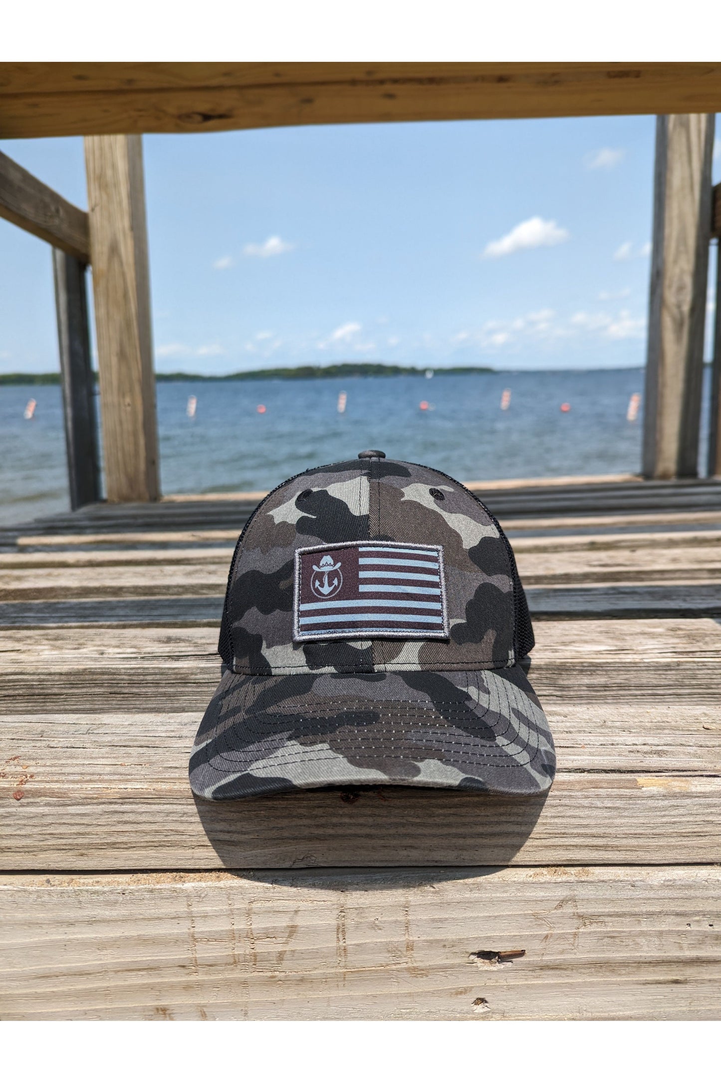 Photo of a Lake Cowboy Camo Baseball Hat (with Patriot Flag) shown as a closeup photo of the hat sitting on a Lifeguard Tower on Lake Minnetonka.