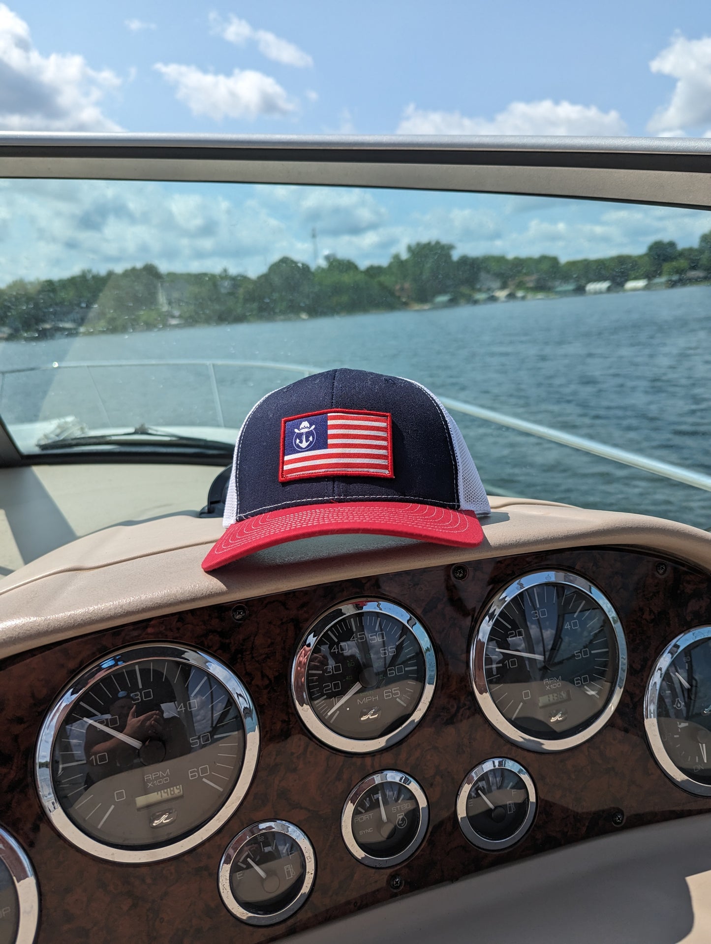 Photo of a Lake Cowboy Patriot Baseball Hat (with Lake Cowboy Patriot Flag) sitting atop a boat console. Photo taken on Lake Minnetonka.