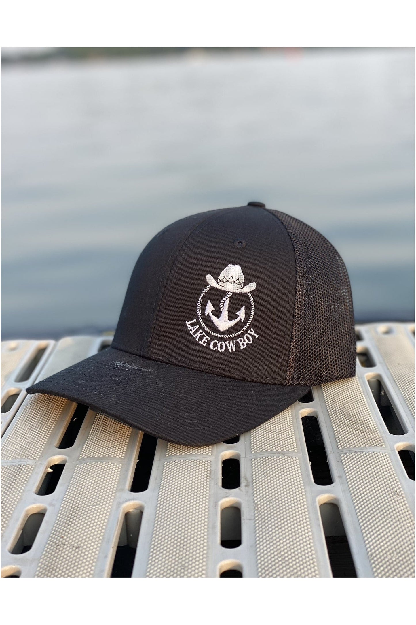 Photo of a Lake Cowboy Baseball Hat (All Black) on a dock on Lake Minnetonka