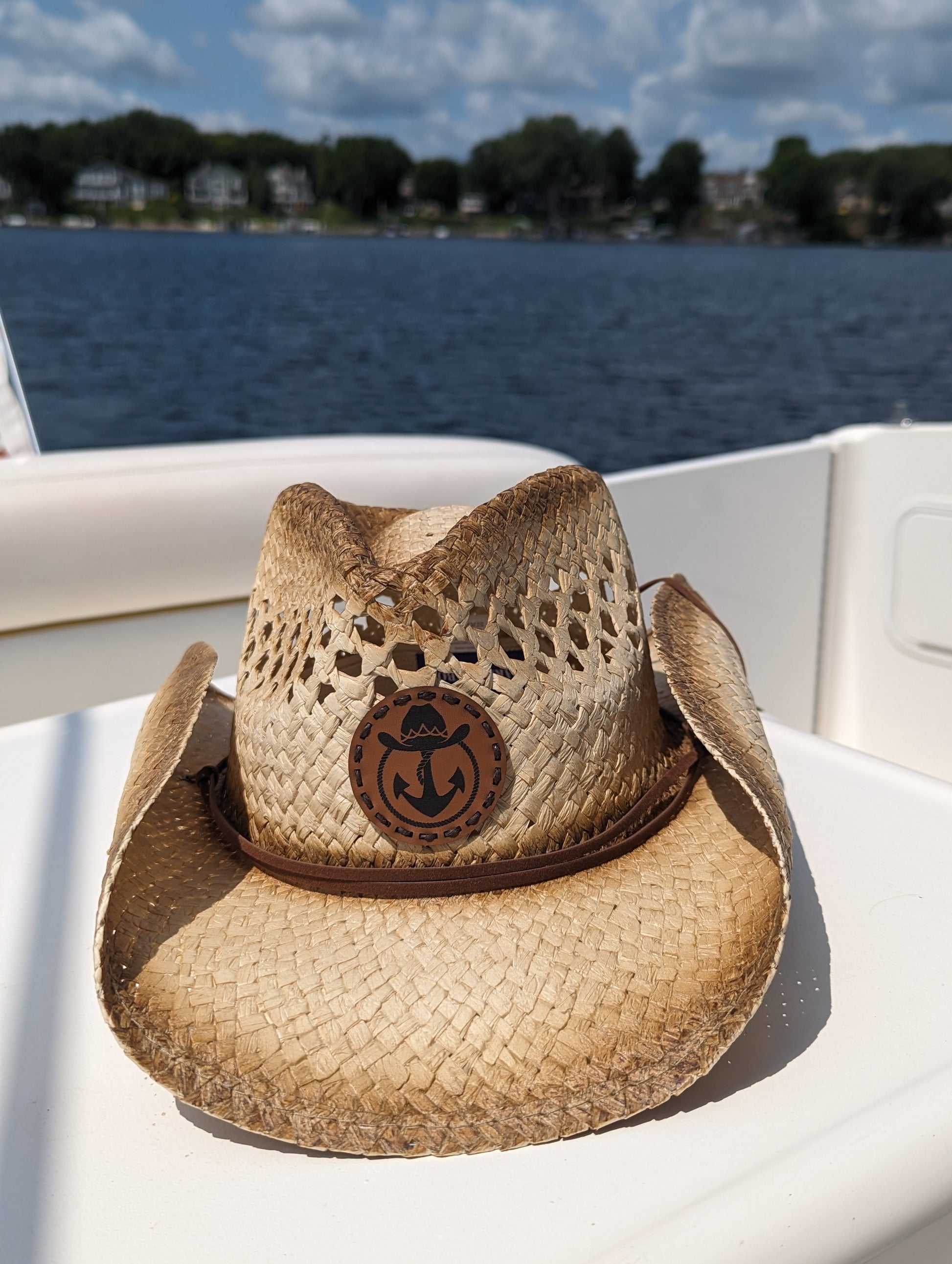 Photo of a Lake Cowboy Signature Cowboy Hat with the iconic hat, lasso and anchor logomark on the front of the hat. The hat is shown sitting on a table on a boat on Lake Minnetonka, MN.