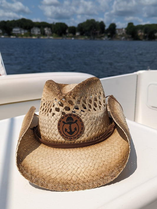 Photo of a Lake Cowboy Signature Cowboy Hat with the iconic hat, lasso and anchor logomark on the front of the hat. The hat is shown sitting on a table on a boat on Lake Minnetonka, MN.