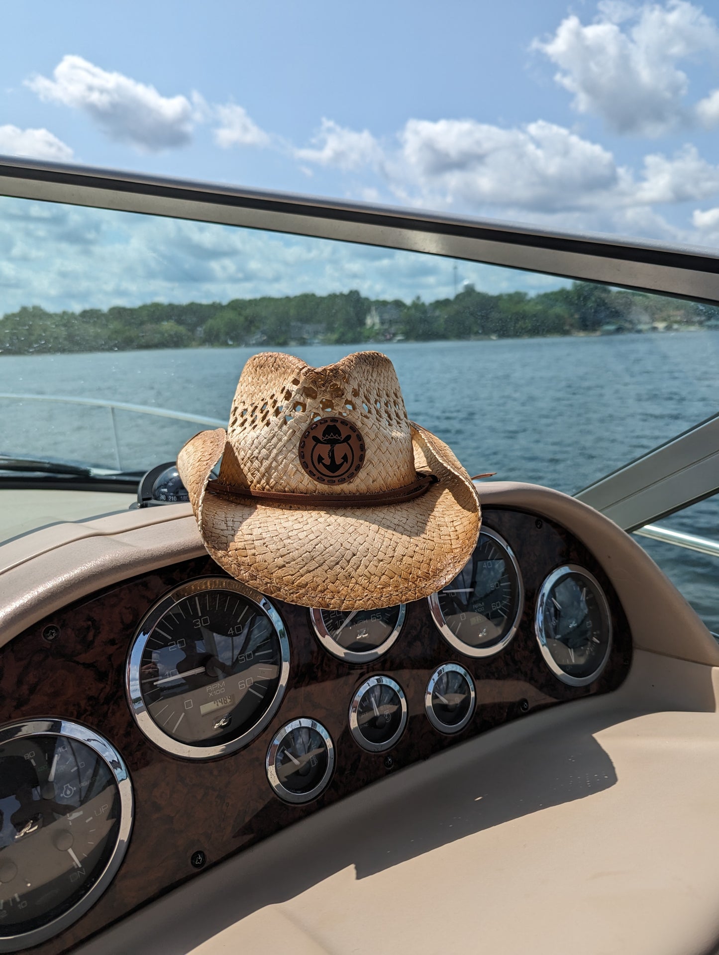 Photo of a Lake Cowboy Signature Cowboy Hat sitting atop a boat console on a sunny day on Lake Minnetonka.