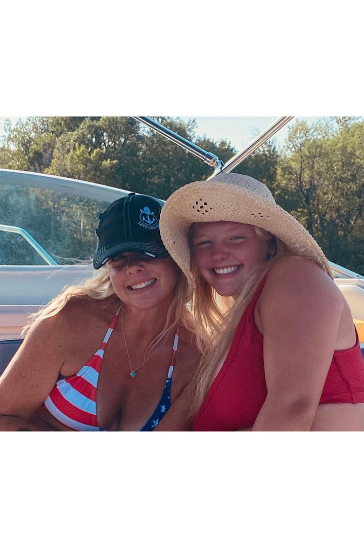 Photo of Lake Cowboy Instagram Models Jenn and Taylor wearing  a Lake Cowboy Sportsman's Trucker Hat (Black) on a boat on Lake Minnetonka