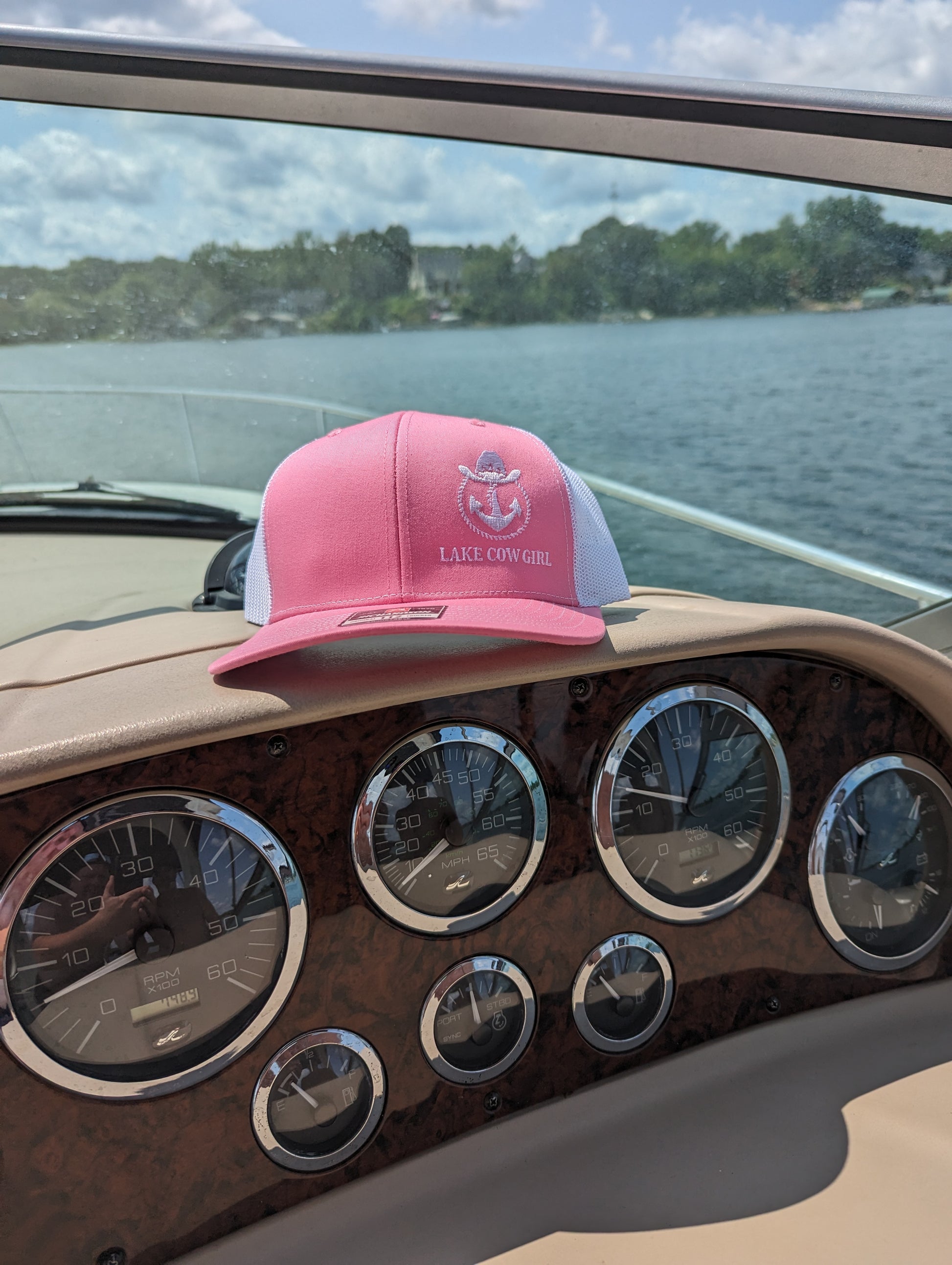 Photo of a Lake Cowgirl Pink Baseball Hat shown sitting atop a boat console. Photo taken on Lake Minnetonka.