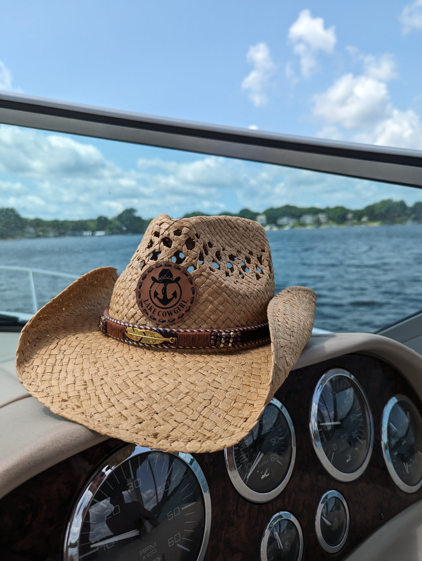 Photo of a Lake Cowgirl Signature Cowboy Hat with Feather Band (Tea Colored) – Shown on a boat console on Lake Minnetonka.