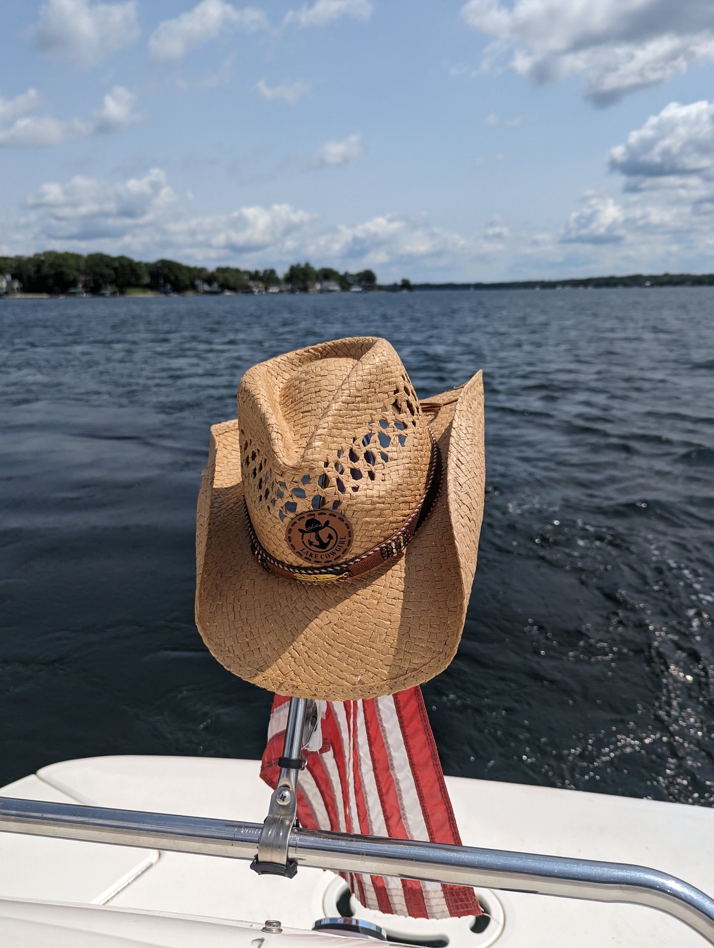 Photo of a Lake Cowgirl Signature Cowboy Hat with Feather Band (Tea Colored) – Hat is shown hanging from a boat flag on the back of a bot on Lake Minnetonka.